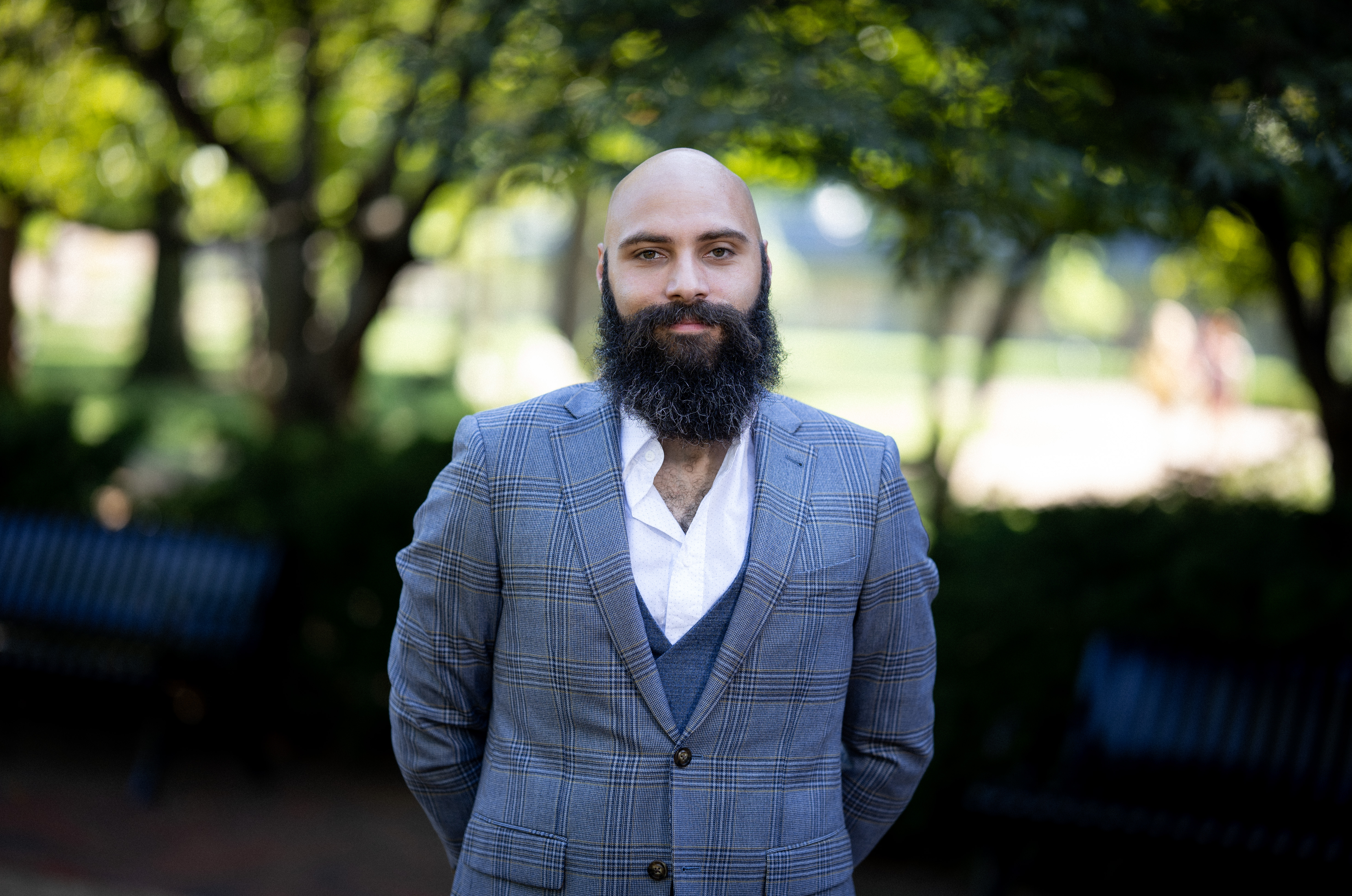 Photo of Matthew Hayes with a dark beard and bald head in a blue suit and white shirt