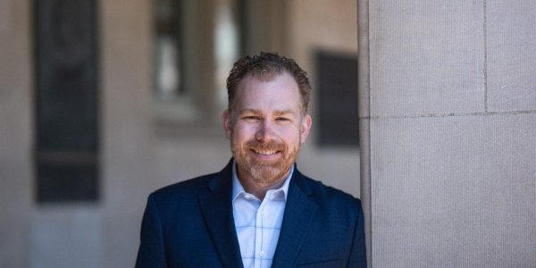 Photo of Jacob Montgomery smiling in a suit jacket and blue shirt