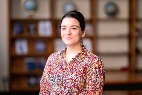 Photo of Mariah Pugliese in a library smiling in a multi-colored top