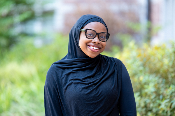 Photo of Maryam Oyebamiji smiling in glasses wearing a black head scarf