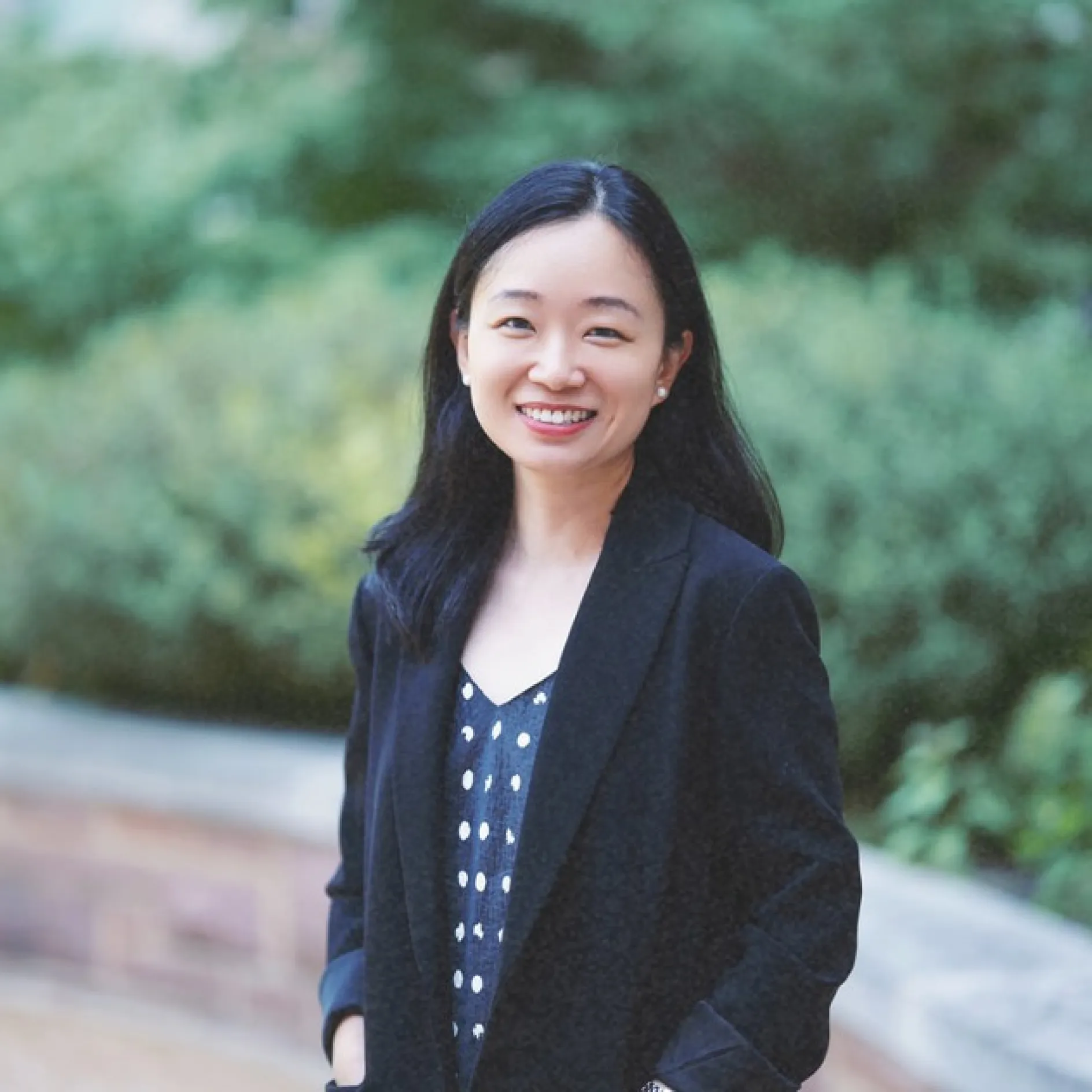 Photo of Peng Peng smiling to camera in a black blazer and patterned top