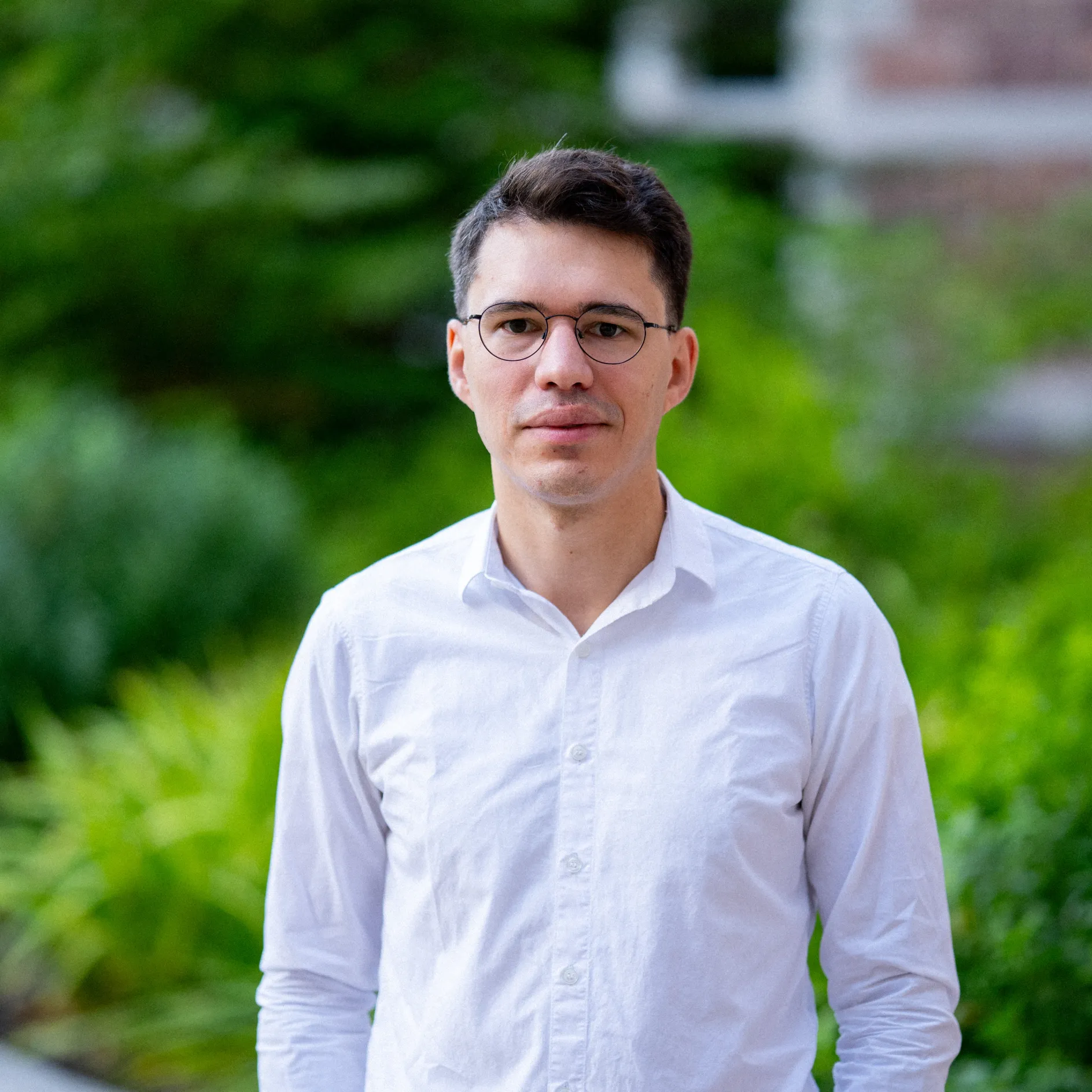 Photo of Juan Dodyk smiling to camera in a white button up shirt