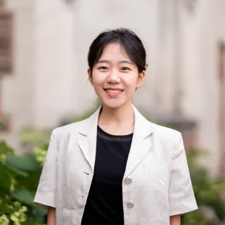 Photo of Soyeon Jeon smiling in a white jacket and black shirt