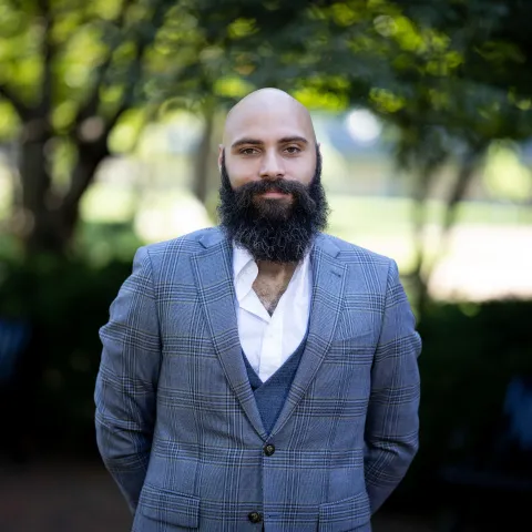 Photo of Matthew Hayes, bald man with a medium length bear, looking directly to camera in a blue blazer and white button up